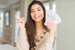 © Krakenimages.com - Young woman holding 50 dollars bank notes very happy pointing with hand and finger to the side