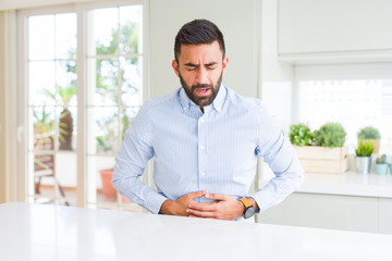 Wall Mural - Handsome hispanic business man with hand on stomach because indigestion, painful illness feeling unwell. Ache concept.