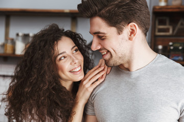 Sticker - Picture of happy couple smiling and hugging together in modern kitchen at home