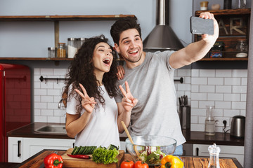 Canvas Print - Picture of candid taking selfie photo while cooking salat with vegetables together in modern kitchen at home