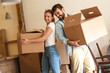 © BalanceFormCreative - Young couple carrying big cardboard box into new home.Moving house.