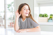 © Krakenimages.com - Beautiful young girl kid wearing stripes t-shirt smiling with hand over ear listening an hearing to rumor or gossip. Deafness concept.