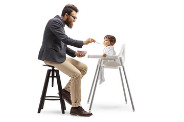 Poster - Father sitting and feeding his baby in a feeding