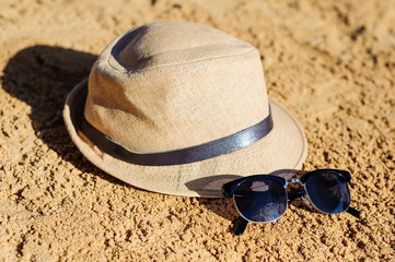 Straw hat and sunglasses on sand beach.