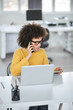 © nenadaksic - Beautiful mixed race businesswoman talking on the smart phone and using tablet while sitting in modern office.