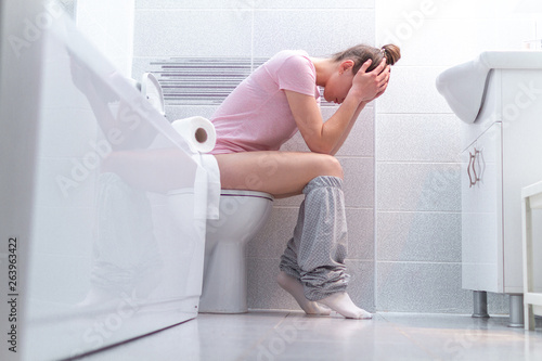 Fotografía Ill, unwell woman suffering from diarrhea, constipation and stomach pain at toilet