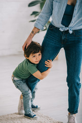 Wall Mural - Cute child in green t-shirt embracing mom in living room