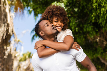 Wall Mural - Outdoor protrait of black african american couple - Guy carrying girfriend on his back