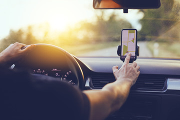 Wall Mural - driver using gps navigation in mobile phone while driving car at sunset