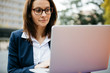 © Westend61 - Businesswoman in the city using laptop