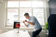© Westend61 - Young businessman at desk in office boxing with punching ball