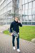 © Westend61 - Smiling young man with skateboard talking on cell phone in the city