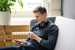 © Westend61 - Smiling young man with tablet and headphones sitting on couch