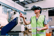 © twinsterphoto - Industrial factory and manfacturing engieering worker wearing VR goggle headset touching in virtual reality simulation alongside heavy duty machines