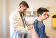 © Cavan Images - Doctor examining teenage patient with a stethoscope in a clinic.