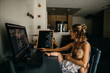 © Cavan Images - Woman holding her daughter while working on laptop at home