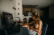 © Cavan Images - Working mother multitasking on the computer and holding baby