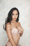 Fototapeta Na drzwi - sexy and gorgeous asian filipino woman with long curly hair and soft skin posing in front of a backdrop in pink lingerie set with her bra strap off her shoulder