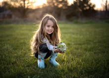 Happy Young Girl  Wearing Rain Boots And Holding Green Plant