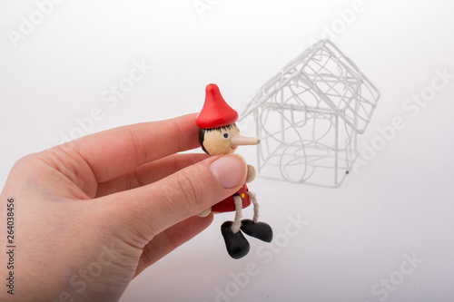 Hand holding pinocchio beside a model house