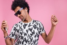 Portrait Of An African Man Dancing On A Pink Background Listening To Dance Music Through Headphones