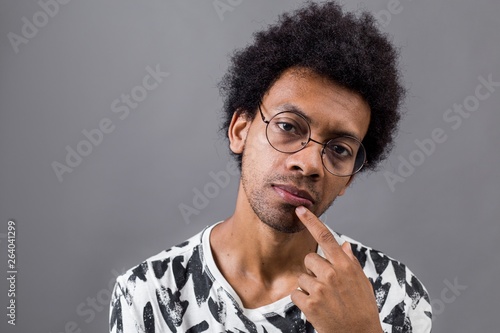 Portrait Of A Pensive African Curly Haired Man In Glasses On Gray