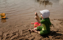 Little Girl In Bonnet Playing With Brother At The Beach