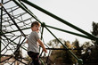 © Cavan Images - Young boy climbing a spider web at the park