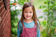 © Cavan Images - a happy little girl stands in a garden looking up