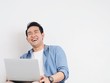 © Mallika - Happy Asian man using laptop at home.