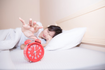 Young sleeping woman and alarm clock in bedroom at home