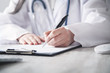 © andranik123 - Doctor writing in a clipboard at clinic.