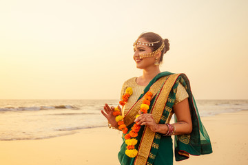 beautiful woman indian wearing green fashion sari, bindis and paint. Close up of beauty indian woman with perfect makeup tikka , nath,nose pin in summer Goa beach in India ocean .tourist photosession