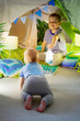 © kostikovanata - Baby toddler crawling to brother on the carpet on the background of a children's tent