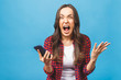 © denis_vermenko - Portrait of a furious young business woman yelling at mobile phone isolated over blue background.