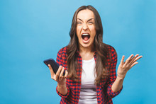 Portrait Of A Furious Young Business Woman Yelling At Mobile Phone Isolated Over Blue Background.