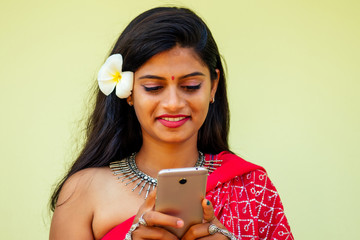 happy india business lady white toothy smile in traditional Indian sari clothes red wedding dress holding a gadget in hand using the phone app in tropic island rocks holiday Indian Bay.girl face id