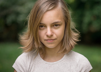 Portrait of attractive caucasian little student girl with beautiful brown eyes. Happy smiling child looking at camera - close-up, outdoors.