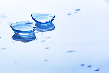 contact lenses and water drops on light blue background. eyewear, eyesight and vision, eye care and 