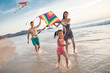 © Blue Jean Images - Happy young family flying a kite on beach