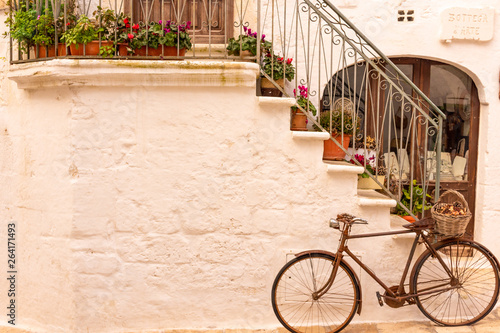 Fototapeta na szkło Italy, Ostuni, old bicycle leaning against the wall, for tourists.