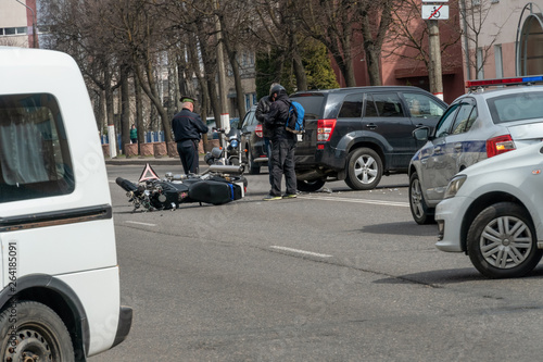 Accident in the city: a broken motorcycle and a car. Registration of a traffic accident. Traffic jam due to an accident, police car, police, people