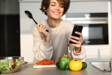 Canvas Print - Image of Smiling brunette woman using smartphone