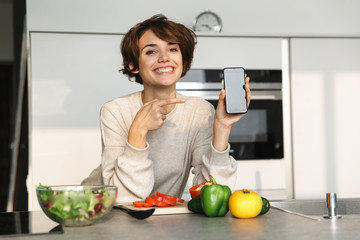 Poster - Happy brunette woman showing blank smartphone screen