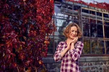 Cute woman on the background of the greenhouse in the autumn park
