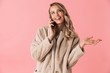 © Drobot Dean - Pleased blonde woman wearing in fur coat talking by smartphone