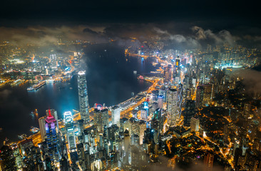 Fototapete - Aerial view of Hong Kong City skyline at night over the clouds