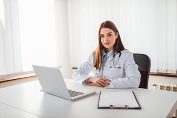 Wall Mural - Portrait of female doctor sitting in office.