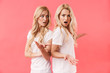 © Drobot Dean - Shocked displeased twins wearing in t-shirts standing back to back