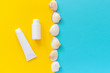 © IRINA - White tube, bottle of sunscreen and line seashells on yellow and blue paper background. Mock up Template for lettering, text or your design Creative Top View Copy space.